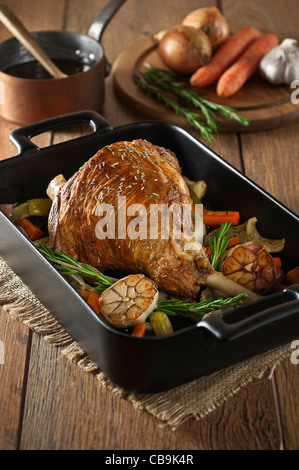 Gebratene Lammkeule mit Knoblauch und Rosmarin in einen Bräter Tablett Stockfoto