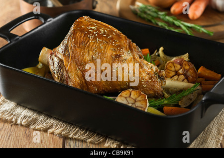 Gebratene Lammkeule mit Knoblauch und Rosmarin in einen Bräter Tablett Stockfoto