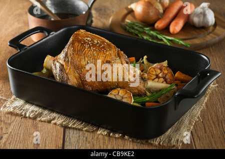 Gebratene Lammkeule mit Knoblauch und Rosmarin in einen Bräter Tablett Stockfoto