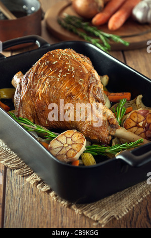 Gebratene Lammkeule mit Knoblauch und Rosmarin in einen Bräter Tablett Stockfoto