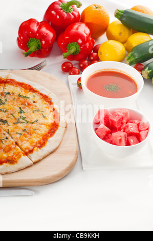 Italienische original dünne Kruste Pizza Margherita mit Gazpacho Suppe und Wassermelone auf Seite und Gemüse auf Hintergrund Stockfoto