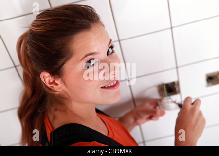 Junge Frau, die Verkabelung einer Steckdose Stockfoto