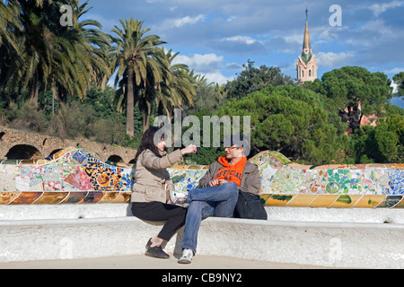 Touristen, die Ruhe auf Bank im Parc Güell / Park Güell, entworfen von Antoni Gaudi, Barcelona, Spanien Stockfoto