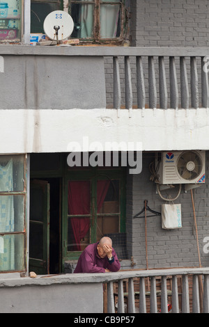 Alte chinesische Mann stützte sich auf seinem Balkon in der Hitze der Provinz Shaanxi Xian, VR China, Volksrepublik China, Asien Stockfoto