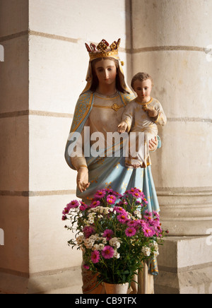 Jungfrau Maria und Jesus-Statue in einer Kirche mit Blumen im Vordergrund Stockfoto