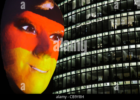 Riesige Skulptur eines Gesichts beleuchtet durch ein Bild von einer deutschen Fahne bemaltem Gesicht während des Festival of lights 2011 in Berlin Stockfoto