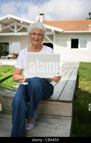 Ältere Frau mit einem Laptop vor ihrem Haus Stockfoto