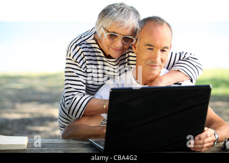 65 Jahre alt paar tun Computer außerhalb Stockfoto