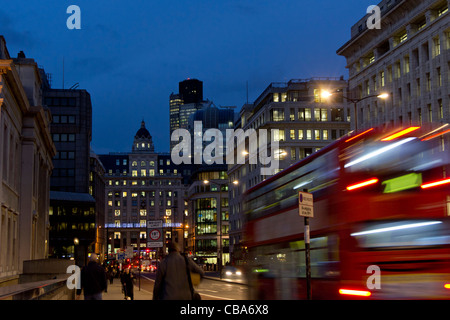 Blick entlang der King William Street von London Brücke der Arbeiter zu Fuß nach Hause, bei Einbruch der Dunkelheit und Bewegungsunschärfe London Bus. Stockfoto