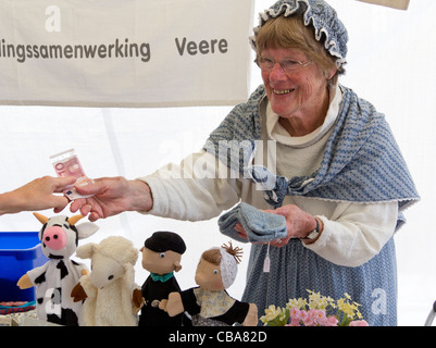 Frau in niederländischer Tracht verkaufen Handwerk Geschenke auf einem historischen Kostüm-Markt in der Stadt Veere, Zeeland, Niederlande Stockfoto