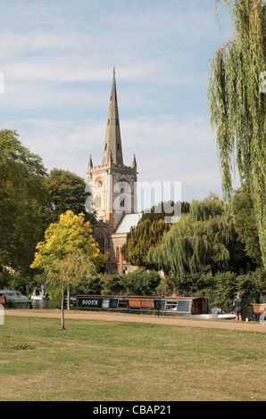 Kanalboote vertäut am Fluss Avon, mit Holy Trinity Church hinter, Stratford Upon Avon, Warwickshire, UK. Stockfoto