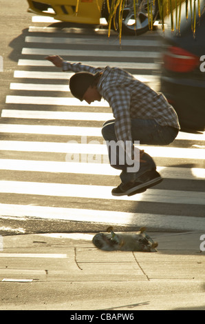 Ein männlicher Skateboarder tut ein Ollie springen Trick auf einem Bürgersteig. Stockfoto