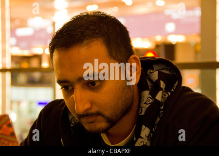 Indischer Mann mit Designer Bart trägt eine schwarze Kapuzenjacke, sieht aus wie er tief in Gedanken versunken ist. Vielleicht ein wenig traurig oder depressiv. Stockfoto