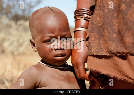 Afrika, Namibia. Porträt eines nomadischen Himba Kindes stehend nahe bei Mutter Stockfoto