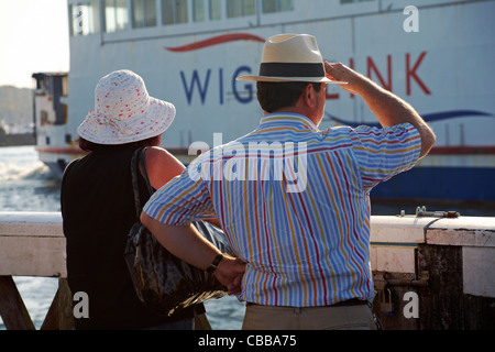 Reifes Paar stand auf Yarmouth Pier und beobachtete eine Wightlink Fähre, die im September an Yarmouth, Isle of Wight, Hampshire UK vorbeifuhr Stockfoto