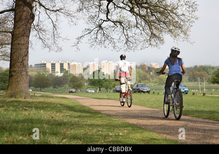 Radfahrer in Richmond Park, Südwesten von London, zeigt die Wohnung Bocks von Roehampton im Hintergrund Stockfoto