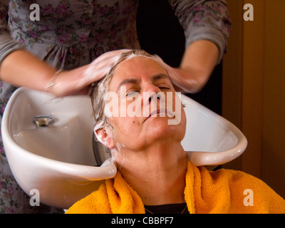 Frau mittleren Alters, die ihr Haar gewaschen in den Friseursalon Stockfoto