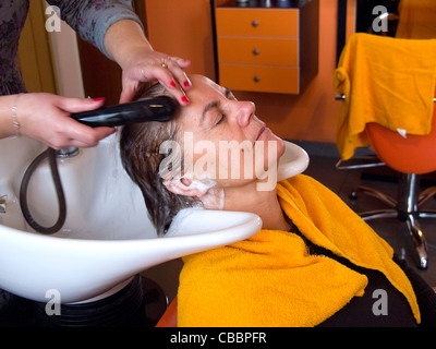 Frau mittleren Alters, die ihr Haar gewaschen in den Friseursalon Stockfoto