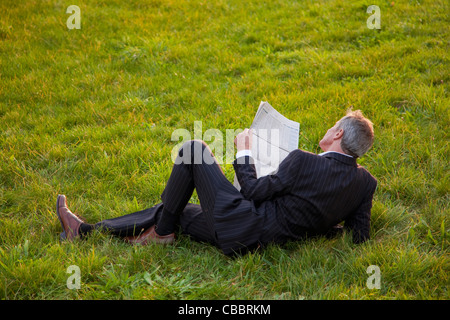 Geschäftsmann lesen Zeitung in Rasen Stockfoto