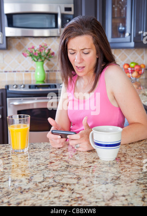 Attraktive Frau mit Pyjamas SMS auf Handy Stockfoto