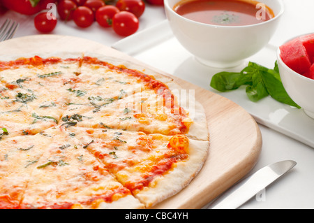 Italienische original dünne Kruste Pizza Margherita mit Gazpacho Suppe und Wassermelone auf Seite und Gemüse auf Hintergrund Stockfoto