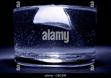 Eis im Wasser in das Glas mit blauen Farbton und schwarzem Hintergrund Stockfoto