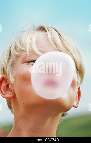 Lächelnde junge bläst Blase im freien Stockfoto
