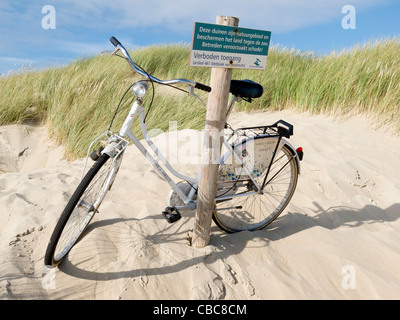 Ein Fahrrad auf den geschützten Dünen am Kop van Schouwen, Nieuw-Haamstede, Zeeland, Schouwen-Duiveland, Schild warnt Hausfriedensbruch. Stockfoto