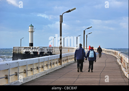 Touristen gehen auf hölzerne Pier bei stürmischem Wetter, Nieuwpoort, Belgien Stockfoto