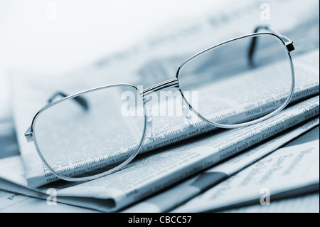 Brille liegen auf einem Stapel Zeitungen. Blau getönt. Ein Foto hautnah. Selektiven Fokus Stockfoto