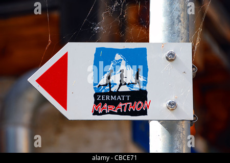 Witzigerweise sehr widersprüchliche Wegweiser zeigt Weg von Zermatt-Marathon.Arrow zeigt eine Möglichkeit, Läufer gehen in entgegen gesetzte Richtung. Stockfoto
