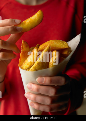 Kartoffel-Keil-Chips in Damen-Hände Stockfoto