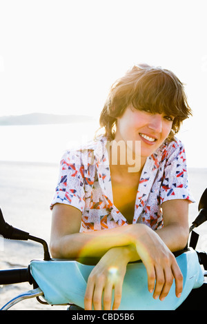 Lächelnde Frau sitzen auf Roller Stockfoto