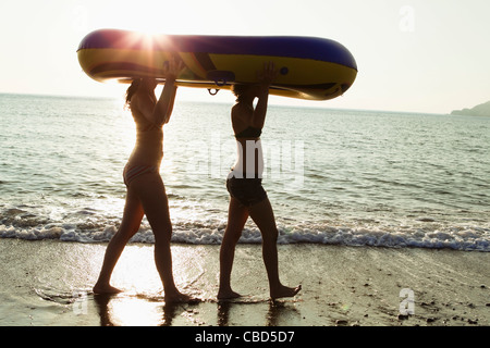 Frauen tragen Schlauchboot am Strand Stockfoto