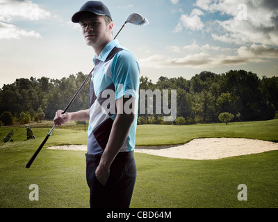 Mann trägt Golfclub auf Kurs Stockfoto