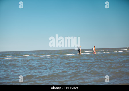 glückliches, junges Paar walking zusammen, umgeben von Wasser, tragen Rucksäcke Stockfoto