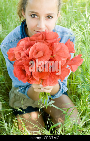 Teen Mädchen kniend im Rasen, holding Bouquet von frischen Mohn Stockfoto