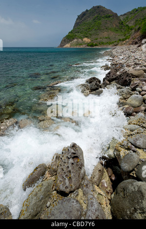 Wellen brechen auf Felsen und Kieselsteine am Ende des Rendezvous Bay, Montserrat Stockfoto