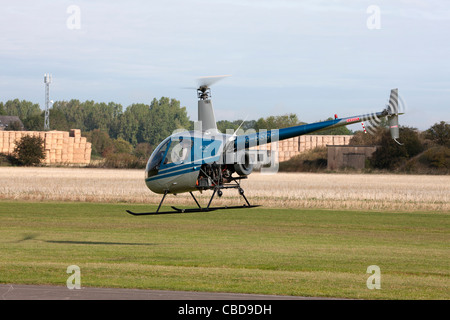 Robinson R22 Beta G-BSGF im Flug niedrig über Start-und Landebahn am Breighton Flugplatz Stockfoto