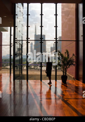 Eine Frau, Blick auf das Guangzhou Opernhaus aus dem Guangdong Museum in der Silhouette. Stockfoto