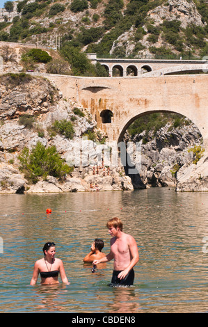 Menschen schwimmen im Fluss Herault, Pont du Diable im Hintergrund, Languedoc Roussillon, Frankreich Stockfoto