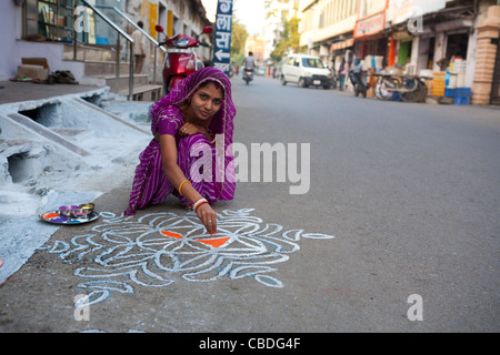 Eine indische Frau dekorieren mit Farbe den Eingang ihres Hauses während Diwali-fest. Stockfoto