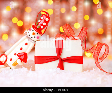 Urlaub-Hintergrund mit niedlichen Schneemann Weihnachtsbaum dekorative Ornament & Geschenk-Box im Schnee über abstrakte Unschärfe Lichter Stockfoto