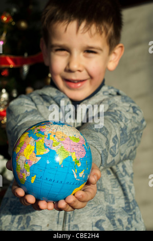 Kind, das als Geschenk die Welt zu Weihnachten zu geben. Stockfoto