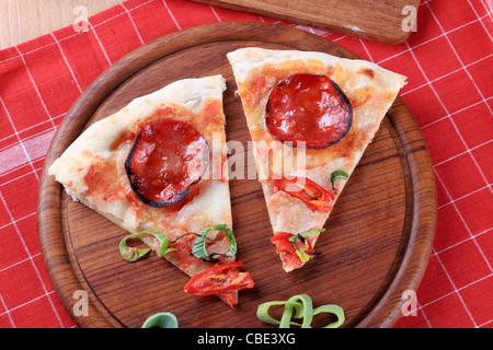 Zwei Scheiben Salami Pizza auf ein Schneidebrett Stockfoto