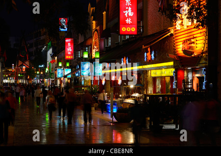 Fußgänger auf Zeng Yang Bu Xing Jie Straße in Guilin an einem regnerischen nasse Nacht mit Lichtern von Geschäften und Restaurants Volksrepublik China Stockfoto