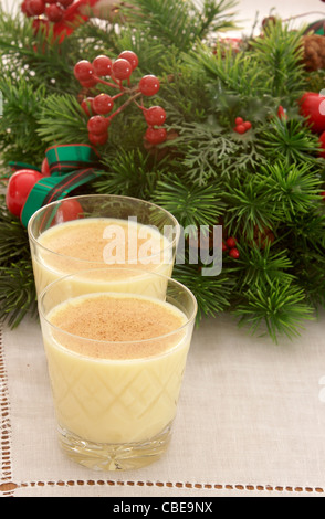 Zwei Gläser Eierlikör, garniert mit Muskatnuss aufgereiht vor ein dekorativer Weihnachtskranz Stockfoto