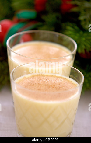 Zwei Gläser Eierlikör, garniert mit Muskatnuss aufgereiht vor ein dekorativer Weihnachtskranz Stockfoto