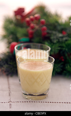 Zwei Gläser Eierlikör, garniert mit Muskatnuss aufgereiht vor ein dekorativer Weihnachtskranz Stockfoto