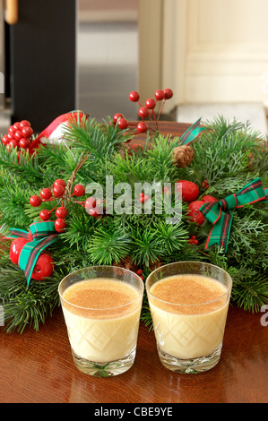 Zwei Kristallgläser von Eierlikör, garniert mit Muskatnuss und eine dekorative Adventskranz. Stockfoto